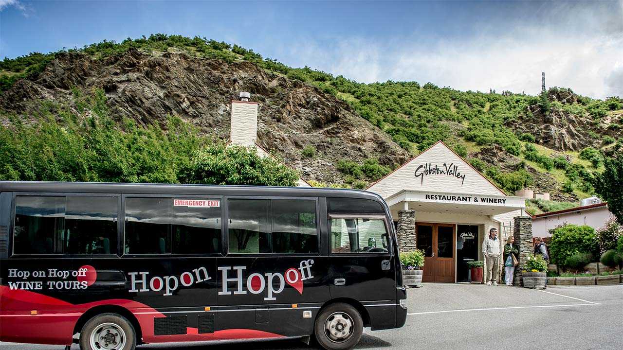 A black Hop On Hop Off wine tour bus outside of a winery restaurant